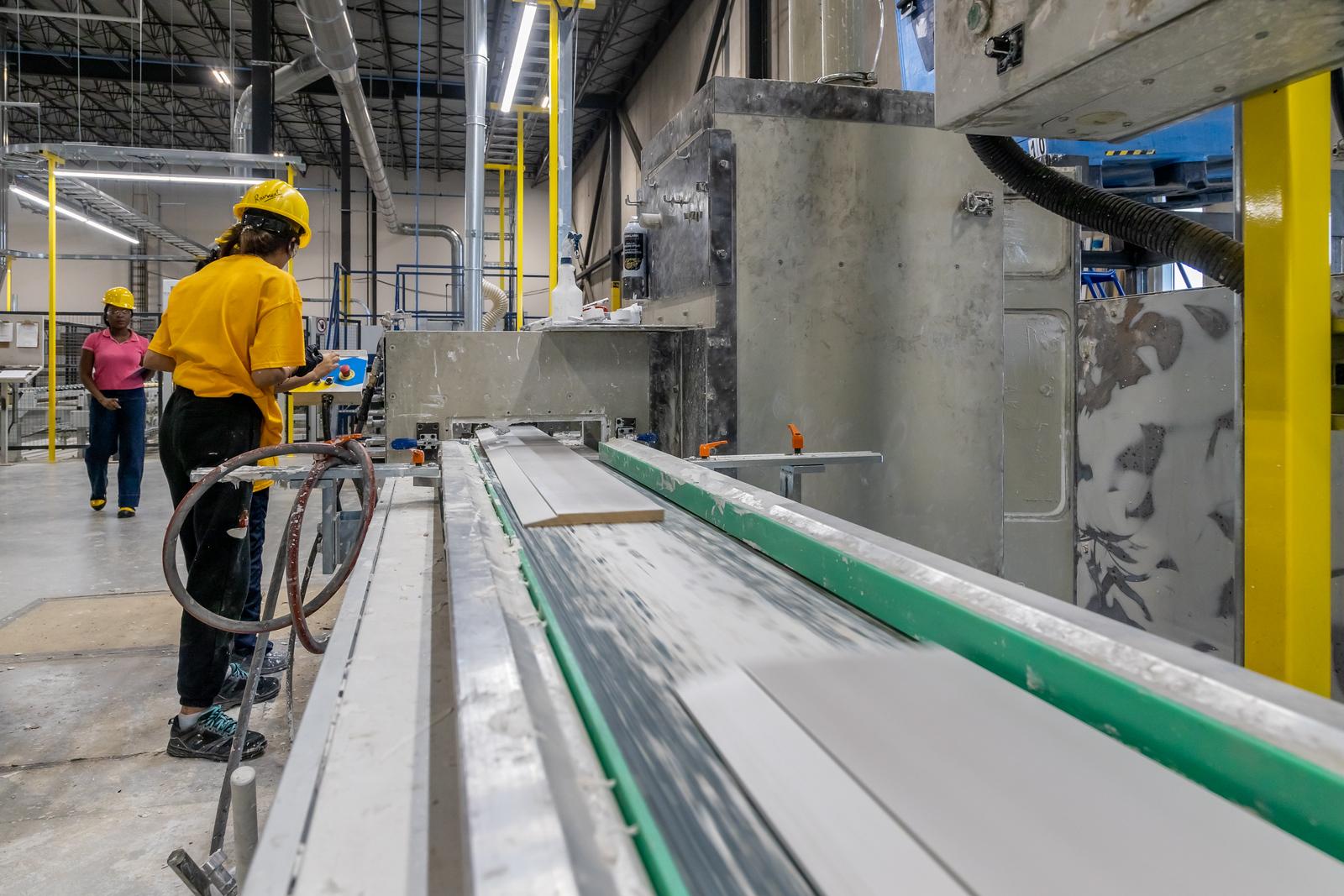 Mujer sobre zócalos de MDF de imprimación dura en una planta de manufactura