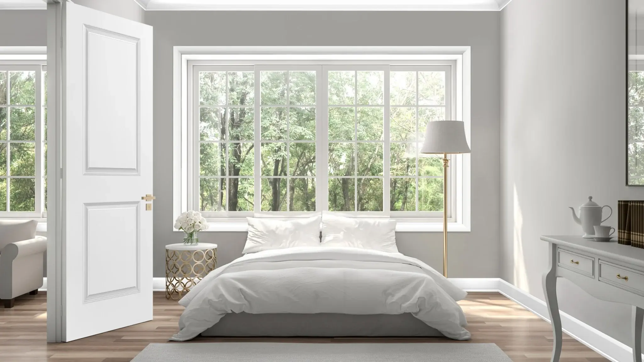 A neutral bedroom white light gray walls, white furniture and bedding. There is a large window above the bed with Polar White Metrie Complete window casing, as well as baseboard and crown. The 2 Panel Metrie Complete pre-painted door opens into the room.